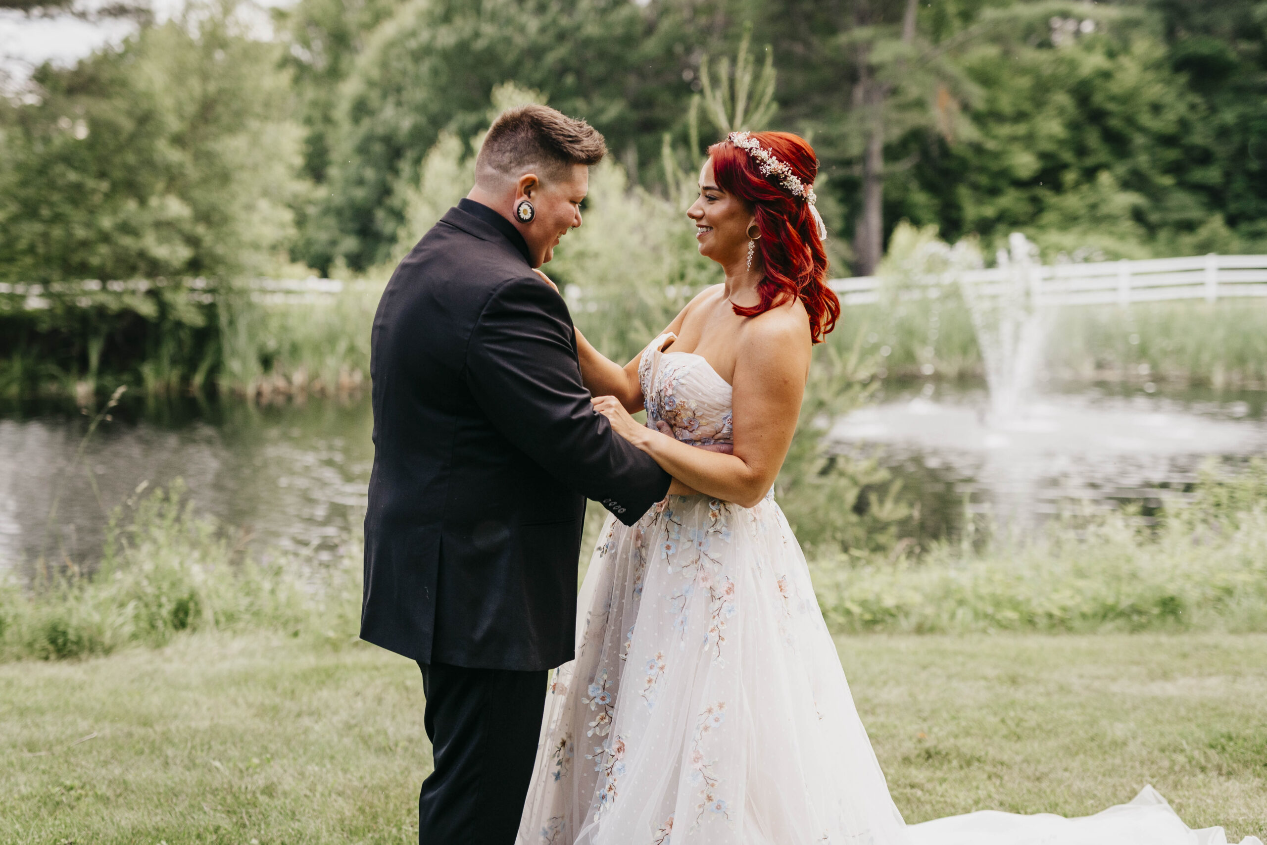 Two brides looking at each other in front of a pond at the New Hampshire Mountain Inn in Wilmot New Hampshire