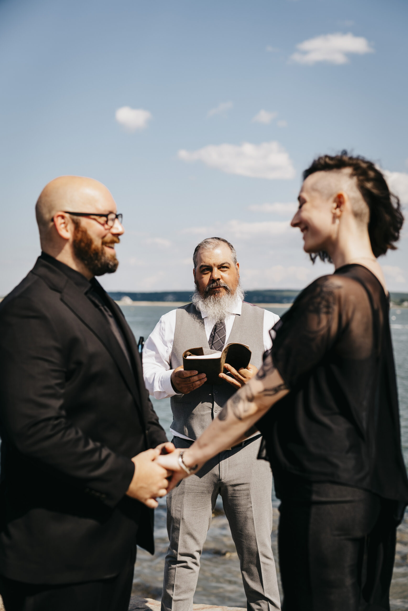 An officiant reads from his book during a ceremony with the bride and groom on the Jetty in Plymouth Massachusetts