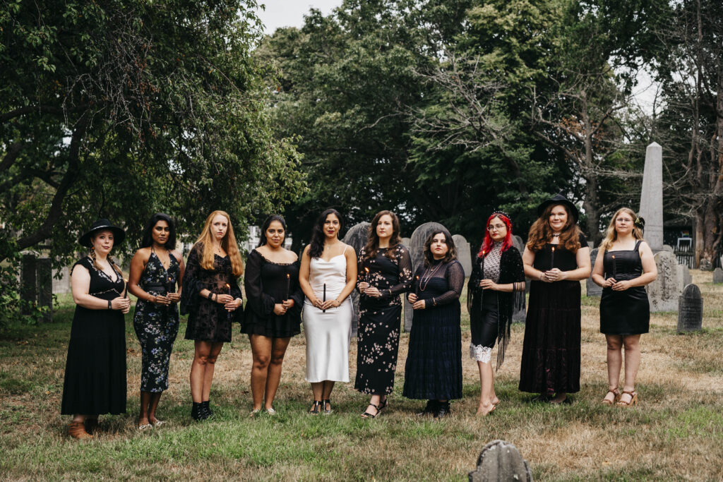 A group of girls pose with black candles at a cemetery in Salem Massachusetts
