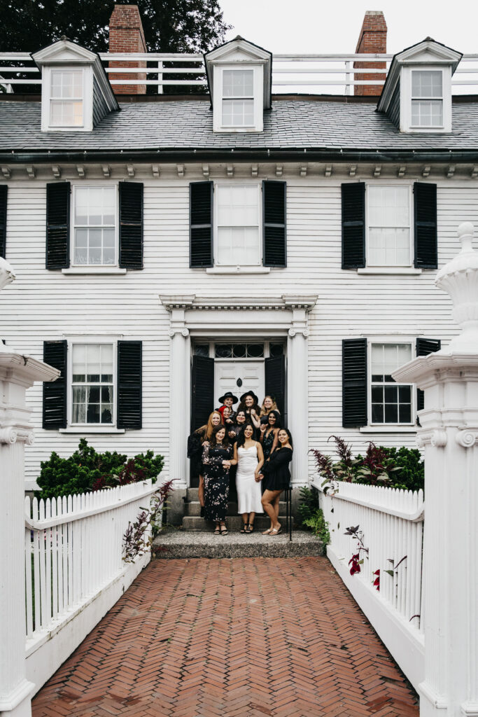 A group of girls hug in front of the Ropes Mansion in Salem Massachusetts